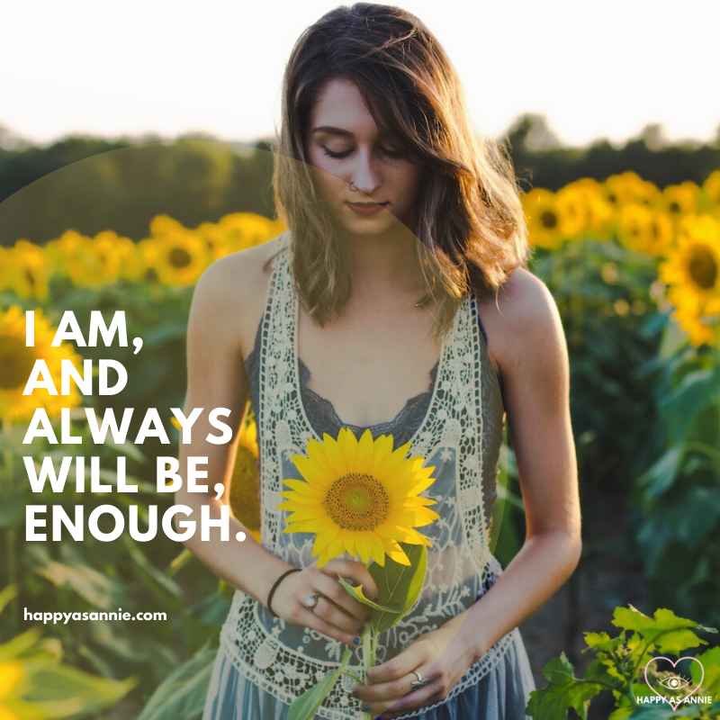 Happy As Annie | 10 Positive Affirmations for Women that Empower and Uplift (Woman in dress standing in sunflower field holding sunflower in front of her with text overlay that says "I am, and always will be, enough."