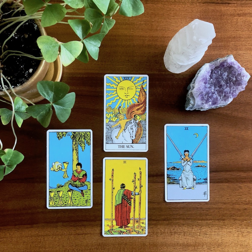 How to Shuffle Tarot Cards - Three Ways to Try Today | Happy As Annie - The classic Rider-Waite tarot deck is a great deck for beginners. (Four cards from Rider Waite deck on wooden table with potted plant and crystals)
