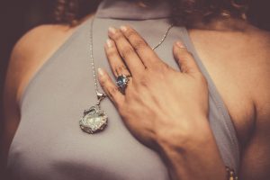 Woman with hand placed on chest, crystal ring and necklace