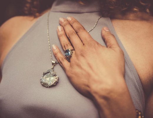 Woman with hand placed on chest, crystal ring and necklace