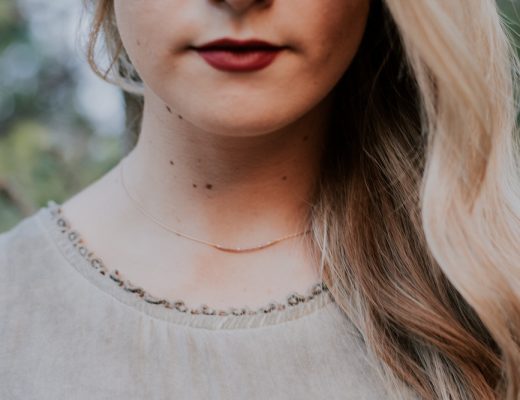 Woman with long blonde hair, red lips, and delicate necklace
