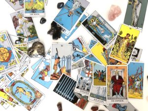 Jumble of Rider Waite tarot cards and crystals against white background