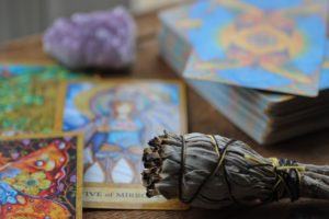 Tarot cards, amethyst, and sage bundle on wooden table