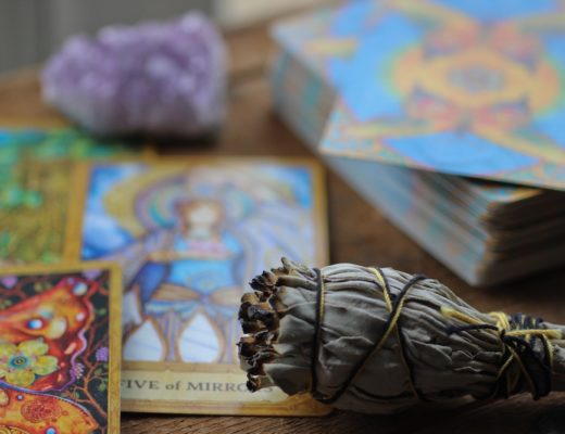 Tarot cards, amethyst, and sage bundle on wooden table