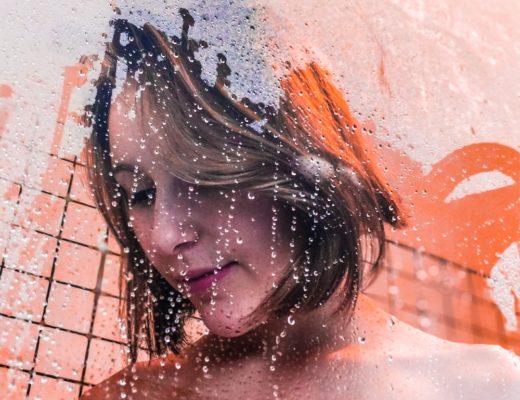 Woman standing in shower behind steamy glass door