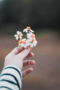 Woman with black and white striped sleeve holding white and yellow flowers in her hand