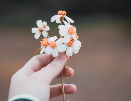 Woman with black and white striped sleeve holding white and yellow flowers in her hand