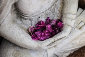 White buddha statue with purple flowers placed in its lap