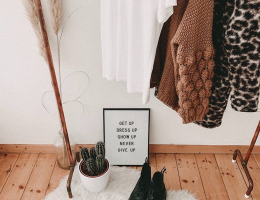 Clothing rack with capsule wardrobe hanging and combat boots and framed quote on floor