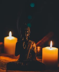 Small buddha figurine next to two lit votive candles