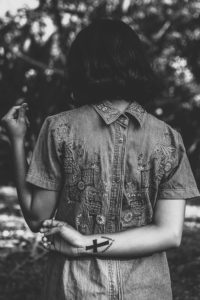 Woman wearing chambray dress with cross tattoo on wrist