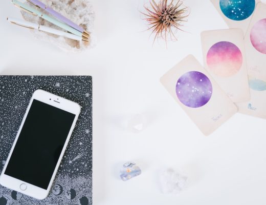 Constellation cards next to notebook and iphone on white table