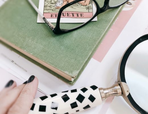 Strength tarot card in French sitting on book with glasses and magnifying glass